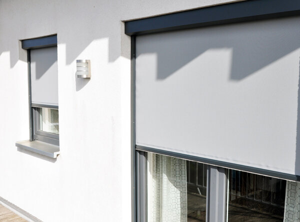 Maßgefertigte Zip Screen Anlage in grau mit blickduchlässigem Sonnenschutz für Fenster und Türen an einem Wohnhaus