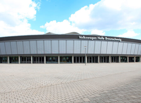 Blick auf die Außenfront einer großen Veranstaltungshalle mit heruntergelassenen Außenjalousien im Obergeschoß