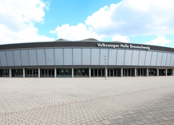 Blick auf die Außenfront einer großen Veranstaltungshalle mit heruntergelassenen Außenjalousien im Obergeschoß