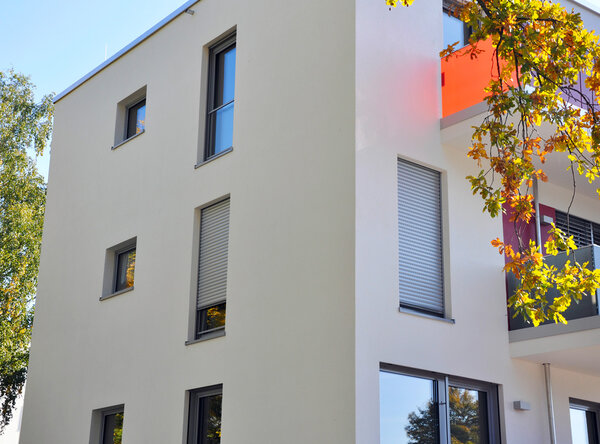 Fassade eines öffentlichen Gebäudes mit Außenrollläden vor den Fenstern, teilweise herunter gelassen.