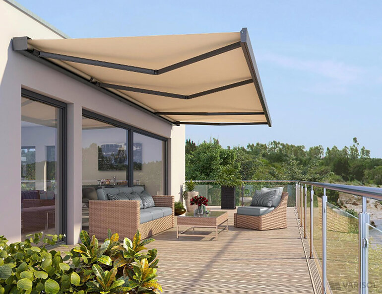 Terrasse von Privathaus bestückt mit Loungemöbeln geschützt durch ausgefahrene Gelenkarmmarkise mit beigem Markisentuch