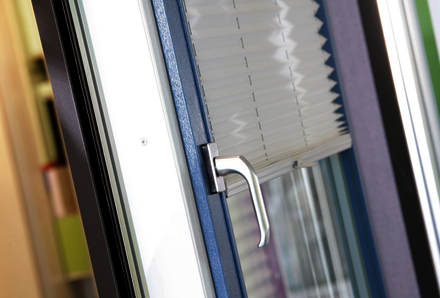Detailansicht eines halbhochgefahrenen Faltstores bzw. Plissees an einer alufarbenden Balkontür