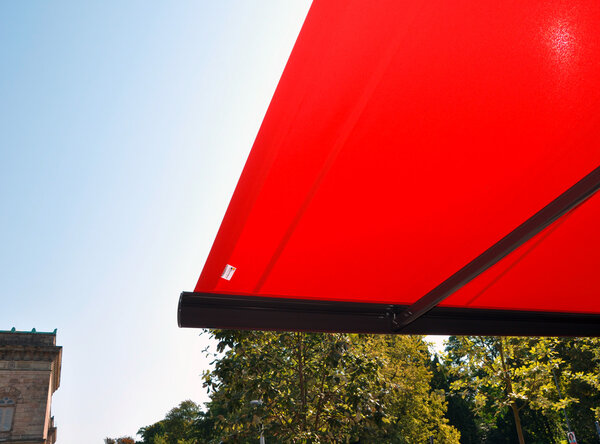 Großflächige Ladenmarkise – mit Detailansichten - in rot als Sonnenschutz für die Außensitzplätze eines Restaurants