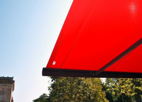 Großflächige Ladenmarkise – mit Detailansichten - in rot als Sonnenschutz für die Außensitzplätze eines Restaurants