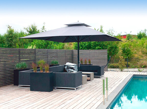 Aufgespannter Sonnenschirm Caravita mit Bodenhülse in schwarz auf der Terrasse neben Loungemöbelsitzgruppe