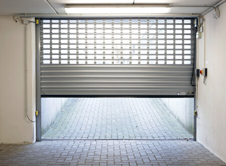 Halboffenes graues Rolltor einer Tiefgarageneinfahrt