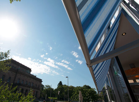 Blau- weiß gestreifte Markisoletten als Sonnenschutz bei freier Durchsicht an der großflächigen Fensterfront eines Cafés
