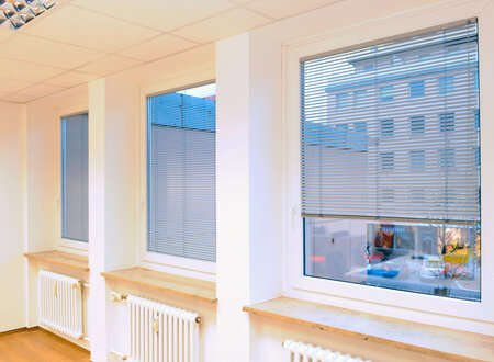 Ausblick durch drei Fenster eines Raumes mit heruntergelassenen Innenjalousien in weiß